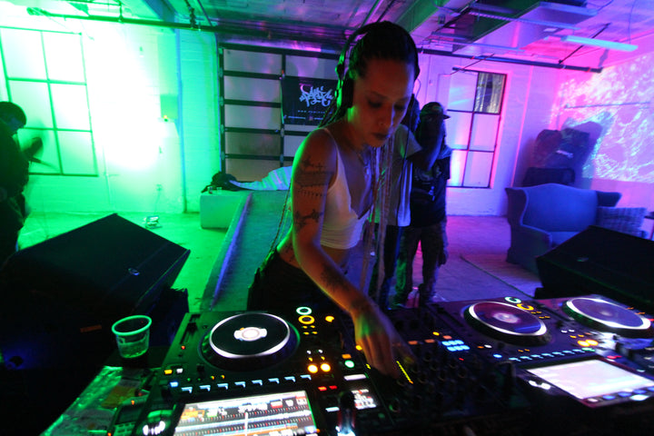 DJ in headphones mixing under green and pink lights at Konkrete Jungle, Los Angeles, February 2024