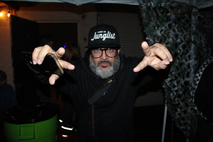 Junglist in a Junglist cap throwing his hands up at Jurassic Jungle / Arkham City, Los Angeles