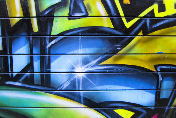 Close-up of a blue and yellow graffiti piece painted on a garage door