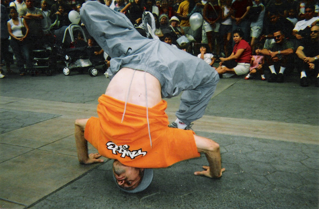 B-Boy Psycho of Air Force Crew and LA Breakers hitting a headstand freeze on pavement in front of a street crowd, early 2000s