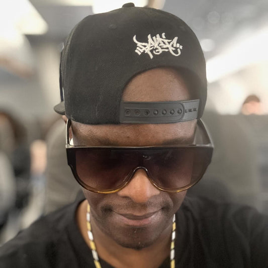 DJ SS in a black Panic 39 tag snapback worn backwards with sunglasses, London