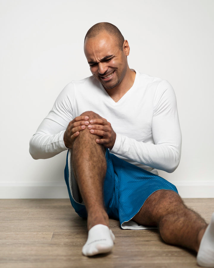 Man sitting on the floor holding his knee in pain