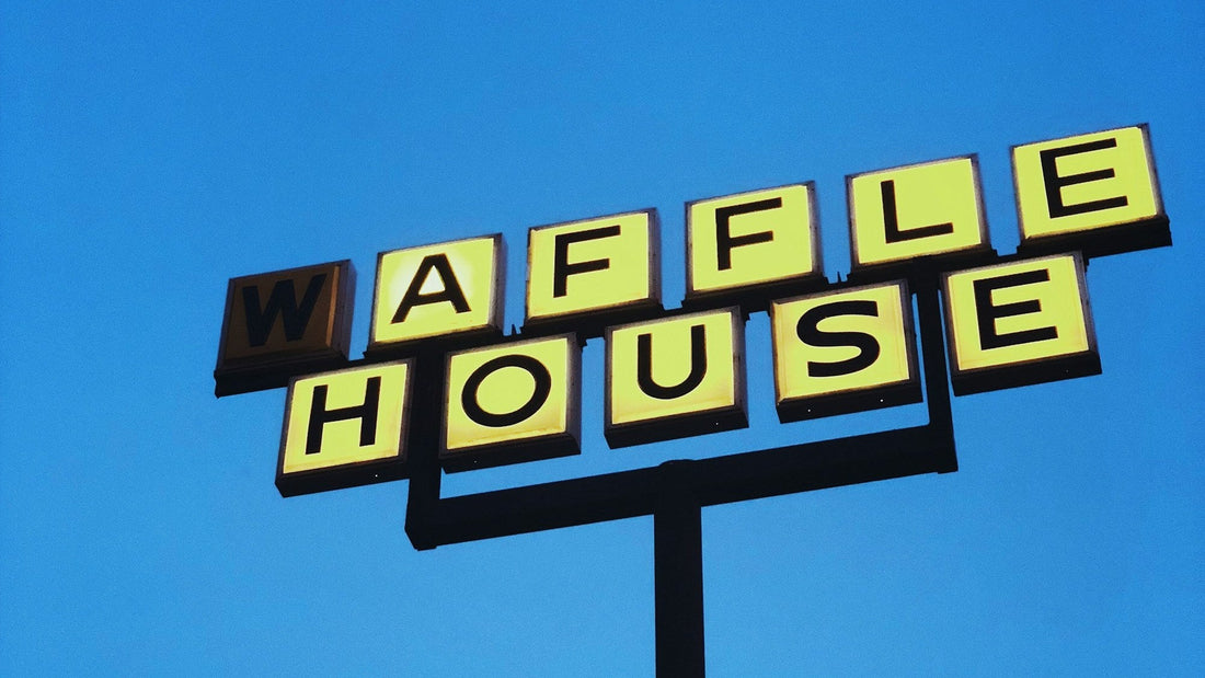 Yellow Waffle House road sign against a deep blue evening sky. Photo: Jon Tyson / Unsplash
