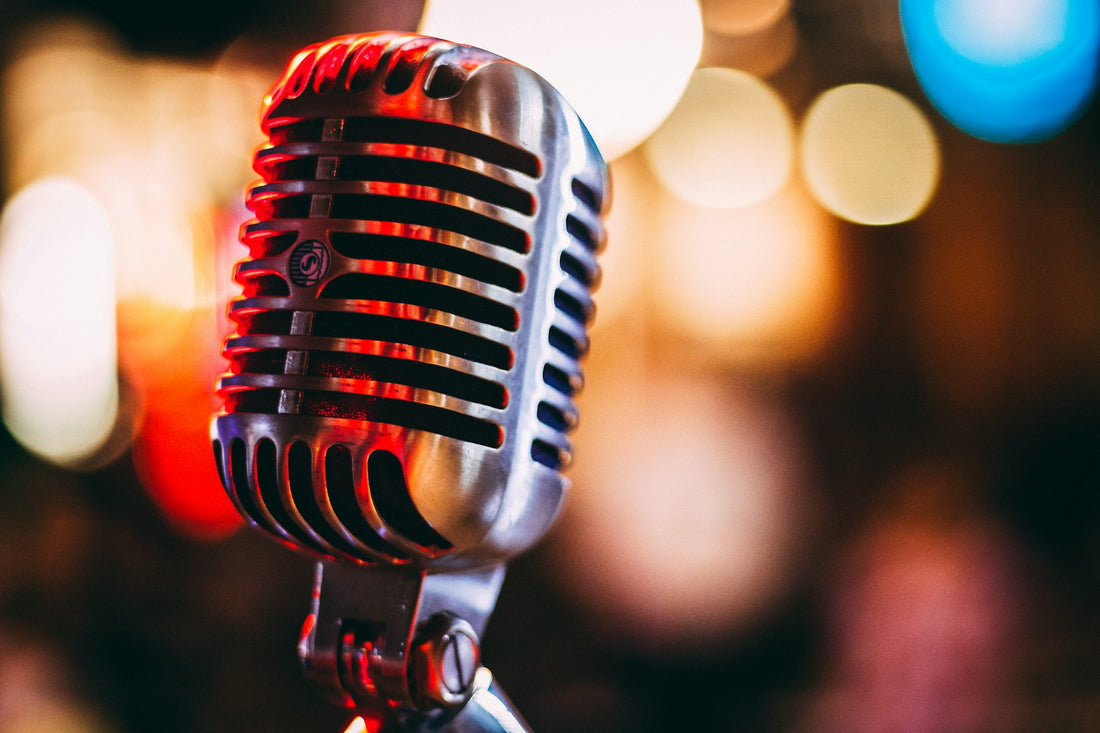 Bokeh photograph of a vintage condenser microphone with neon lights. Photo by israel palacio on Unsplash.