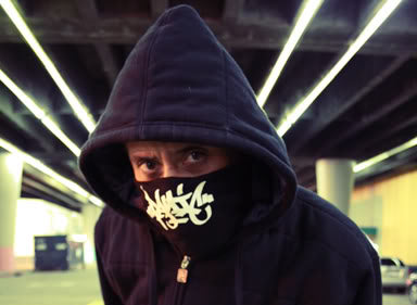 6Blocc aka RAW in a hoodie and Panic 39 face mask under a freeway